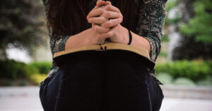 a woman sitting and praying over a bible