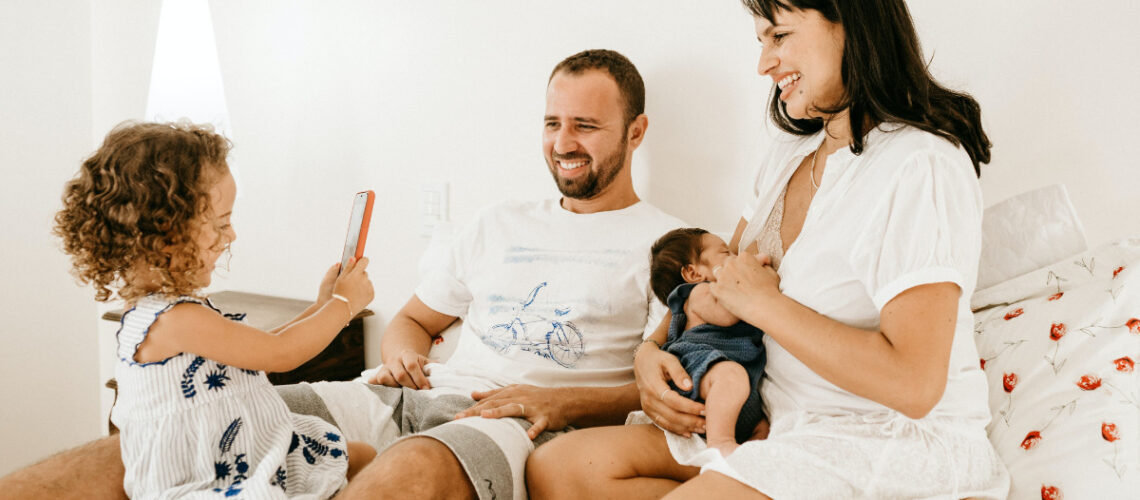 Mother and father sitting on a bed with two children