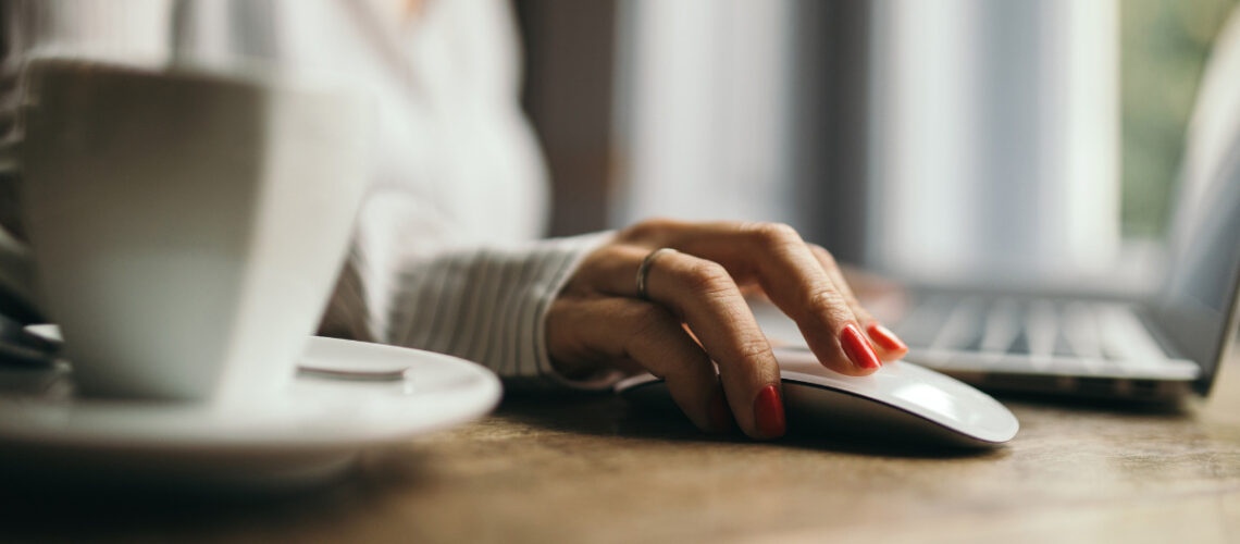 Woman with red nail polish clicking a computer mouse.