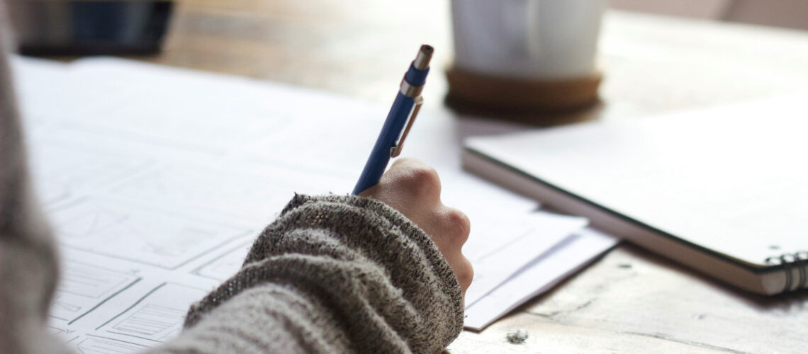 a person using a pen to write in a notebook