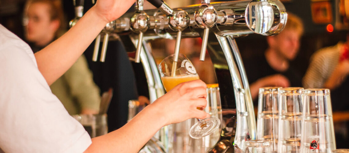 man pouring a beer from a tap at a brewery
