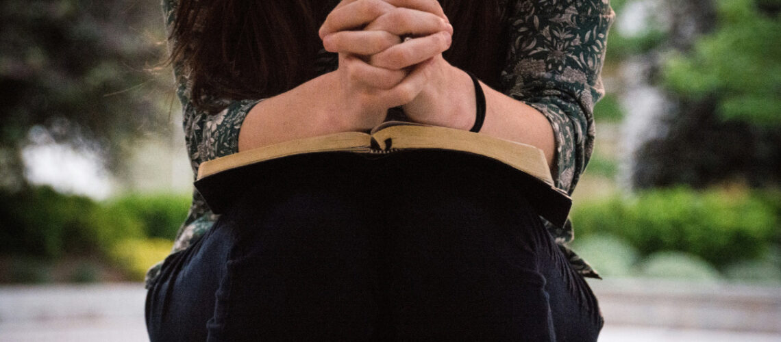 a woman sitting and praying over a bible