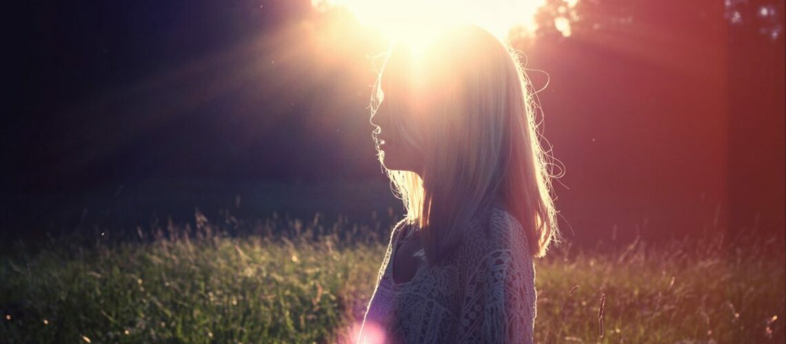 a woman in a field with sunlight