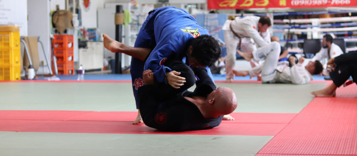 2 men performing martial arts on a matted floor