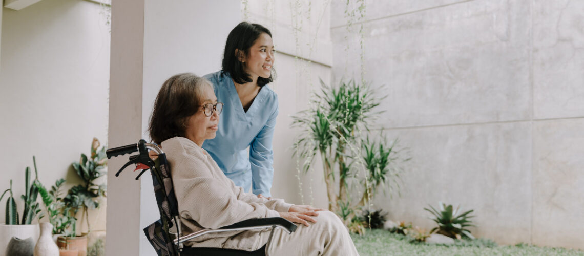 Woman in wheelchair helped by a younger woman.