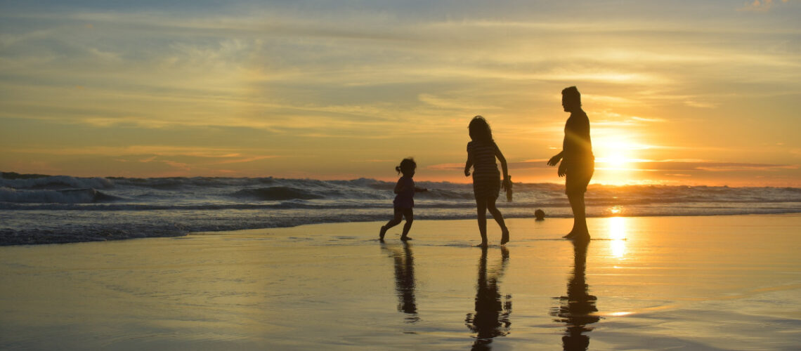 Family spending time together on the beach at sunset.