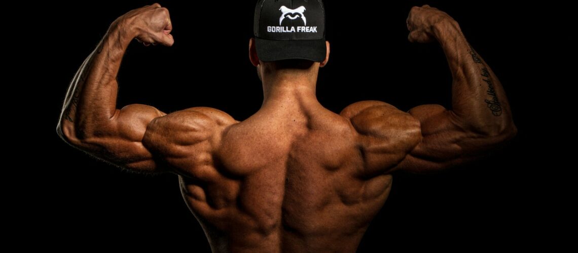 man flexing his back and biceps from behind
