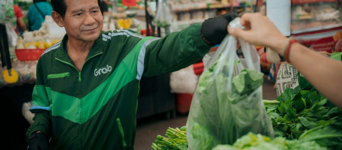 a man holding a bag of lettuce in a market