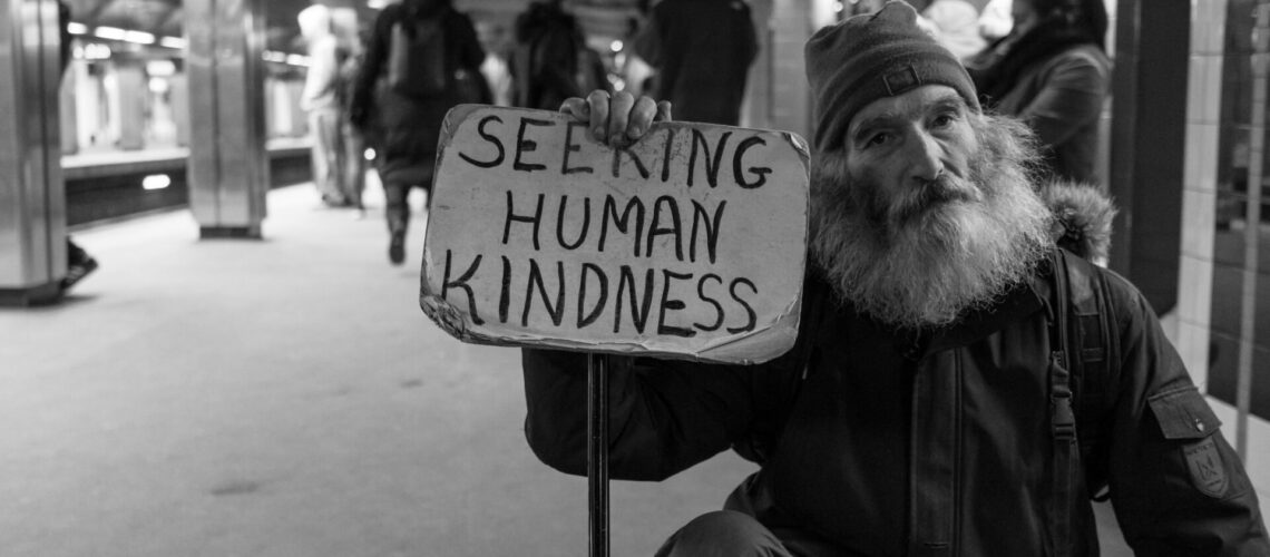 Homeless man with sign that says seeking human kindness