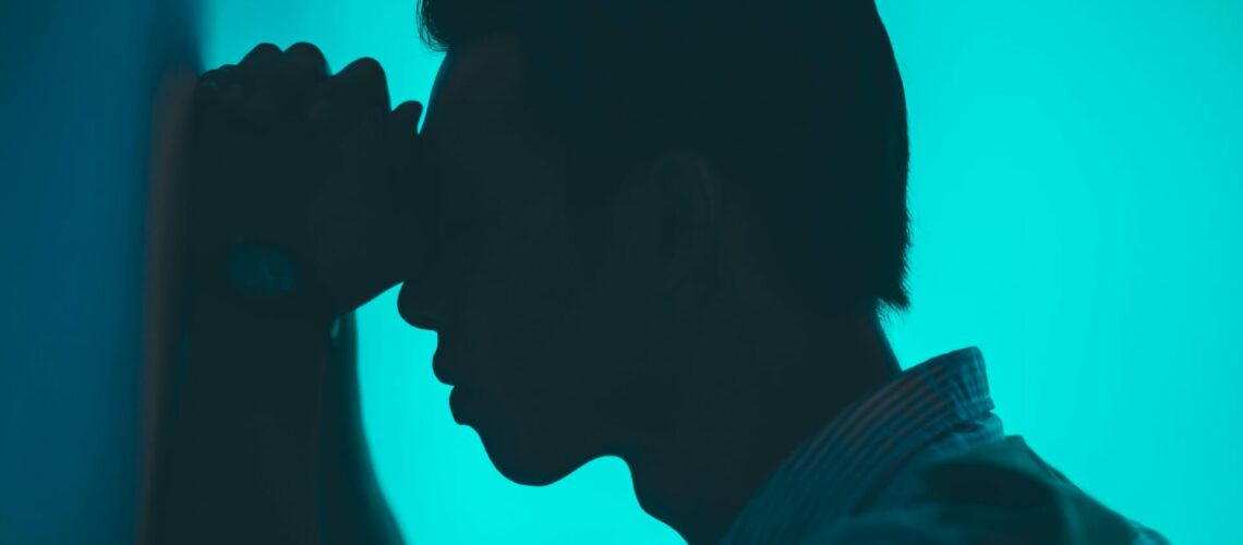 Person resting their head against their hands on a wall